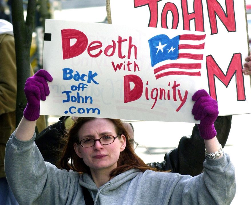 At midnight on Feb. 18, 2017, Washington, D.C. became the 7th jurisdiction in the U.S. to allow physician-assisted suicide. In this March 22, 2002, file photo, Stacey Richter holds a sign outside a federal courthouse in Portland, Ore., as a hearing begins to decide the fate of Oregon's physician-assisted suicide law. (AP Photo/Don Ryan, File)