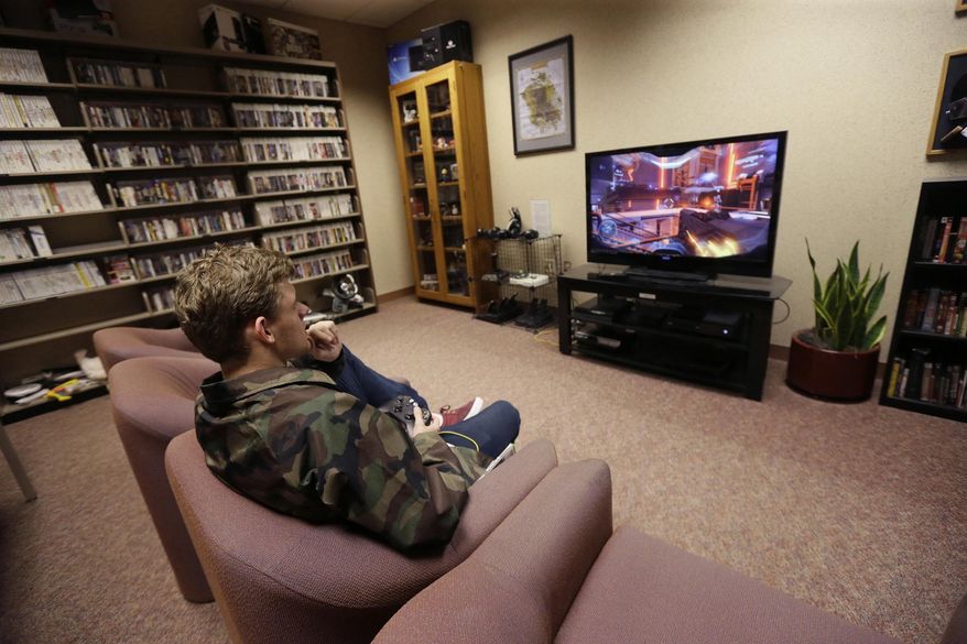 In a photo from Friday, May 20, 2016, Tyler Aman takes a few minutes of his day to play a video game at the Computer and Video Game Archive at the Duderstadt Center at the University of Michigan in Ann Arbor, Mich. The university's archive features over 7,000 titles - everything from time-honored favorites such as "Pac-Man" and "Frogger" to newer fare, including "Call of Duty" and "Halo" - on dozens of gaming systems. And unlike some other video game archives out there, students and members of the public alike are permitted to visit and play any game available, whether for research or just to relax. (AP Photo/Carlos Osorio)