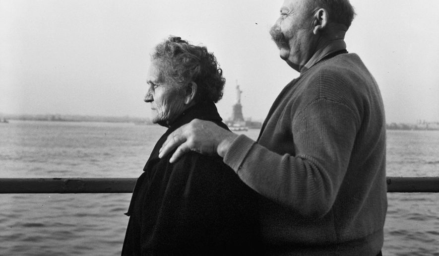 FILE - In this Oct. 28, 1956 file photo, Mr. and Mrs. Paul Roerich from Bavaria, Germany, look out from the stern of the USNS General Langfitt anchored in New York Harbor carrying 1,267 refugees from Europe. In the background is the Statue of Liberty. The couple plan to settle in Ohio. The American self-image is forever intertwined with the melting pot _ a nation that embraces the world’s wretched refuse, a nation built by immigrants. But America’s immigration history is complicated. (AP Photo/File)