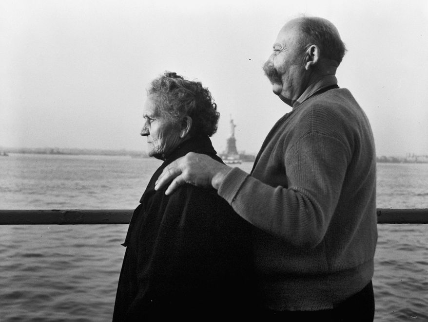 FILE - In this Oct. 28, 1956 file photo, Mr. and Mrs. Paul Roerich from Bavaria, Germany, look out from the stern of the USNS General Langfitt anchored in New York Harbor carrying 1,267 refugees from Europe. In the background is the Statue of Liberty. The couple plan to settle in Ohio. The American self-image is forever intertwined with the melting pot _ a nation that embraces the world’s wretched refuse, a nation built by immigrants. But America’s immigration history is complicated. (AP Photo/File)