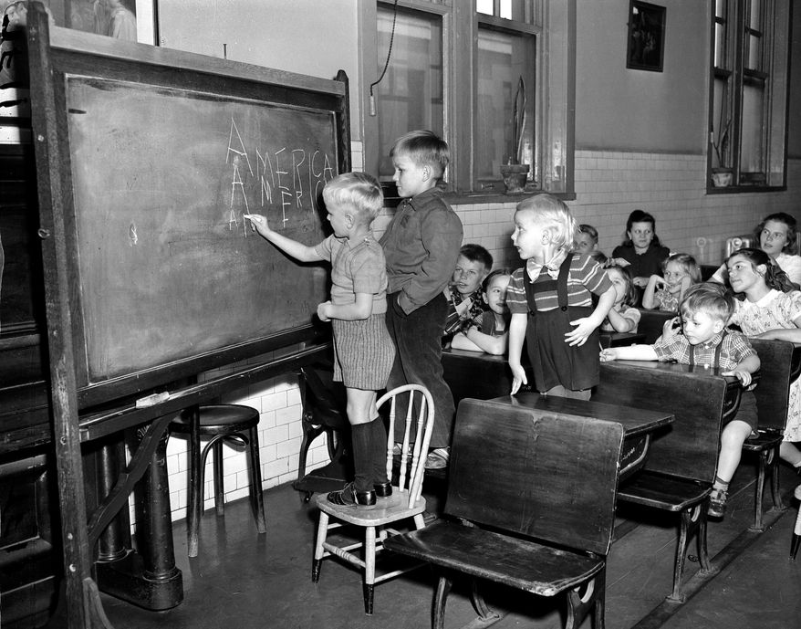 FILE - In this April 7, 1949 file photo, three Finnish children write "America" on a chalkboard in a class held for children of immigrants detained at Ellis Island in New York City. They range in ages 3 to 11 years old. The American self-image is forever intertwined with the melting pot _ a nation that embraces the world’s wretched refuse, a nation built by immigrants. But America’s immigration history is complicated. (AP Photo)