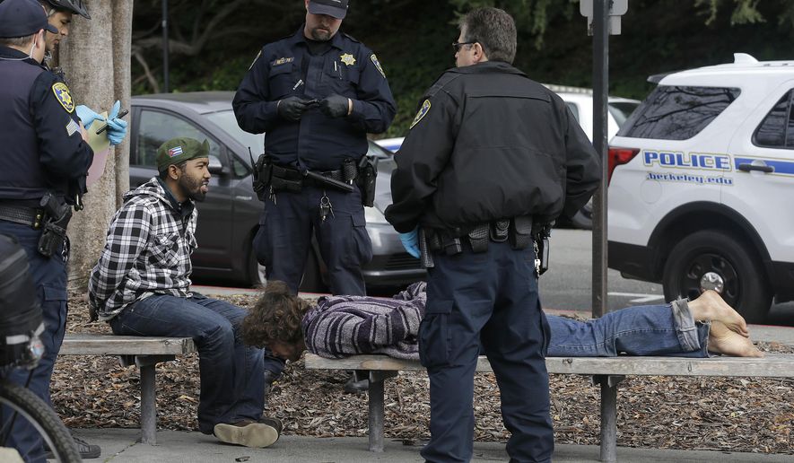 Police officers arrest two men who attacked a student on the University of California, Berkeley campus in Berkeley, Calif., Thursday, Feb. 2, 2017. Jack Palkovic, a student wearing a "Make America Great Again" hat, was attacked on the University of California, Berkeley campus a day after violent protests led authorities to cancel a controversial speech. (AP Photo/Jeff Chiu)