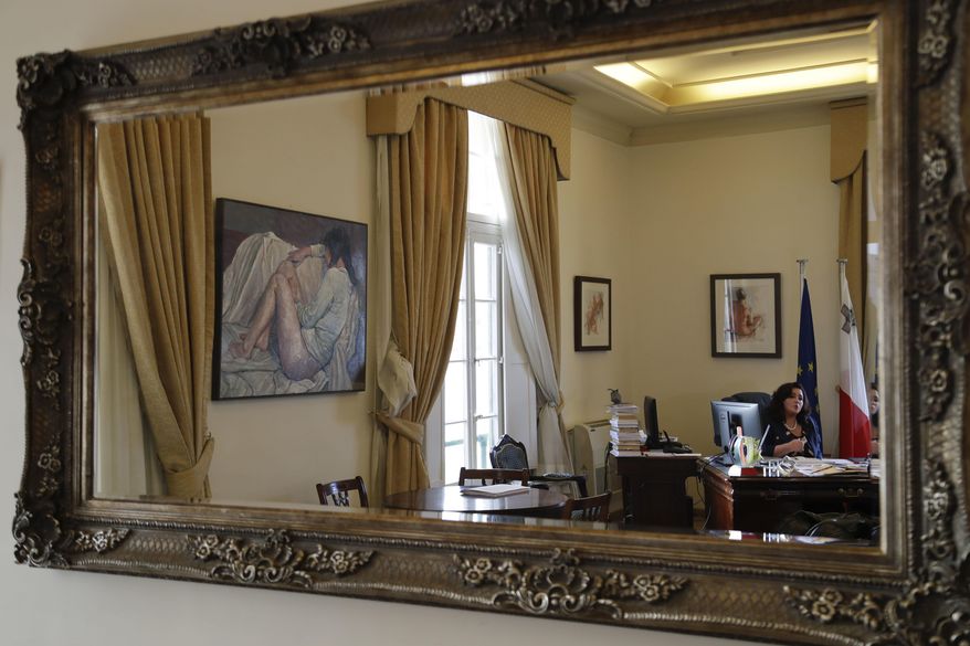 Maltese Minister for Social Dialogue Consumer Affairs and Civil Liberties Helena Dalli is seen pictured in a mirror in her office during an interview with the Associated Press, in Valletta, Wednesday, Feb. 1, 2017. After a quarter-century as Malta's governing party, the conservative Nationalist Party scrambled to line up a transgender young man as a candidate for next year's Parliamentary elections in hopes of reversing a stinging, landslide 2013 loss to its socialist archrivals who came to power with an agenda heavy on LGBT rights. (AP Photo/Gregorio Borgia)