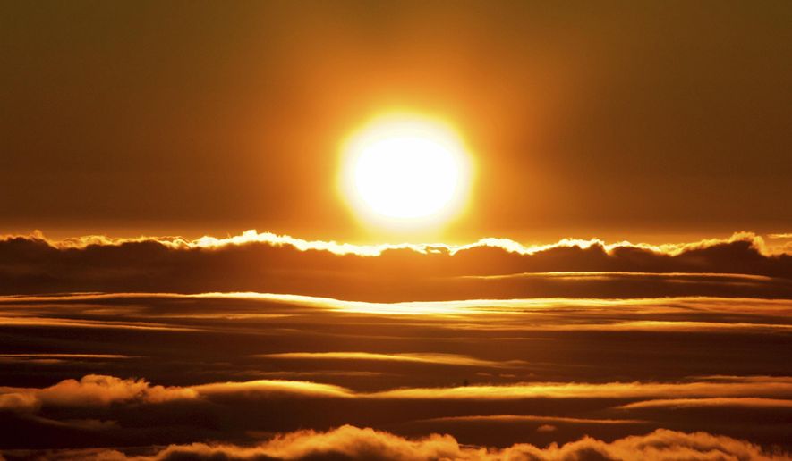 The sun rises over the clouds in front of the summit of Haleakala volcano in Haleakala National Park on Hawaii's island of Maui, Sunday, Jan. 22, 2017. Park officials say the sunrise on Haleakala attracts over a thousand people a day, resulting in an overload of visitors and creating a safety hazard. As a result, anyone wanting to see the sunrise on the summit will now be required to make reservations in advance and pay a small fee. (AP Photo/Caleb Jones)