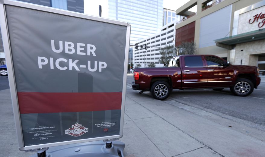 In this Tuesday, Jan. 30, 2017 photo, a sign marks an Uber designated pick-up point near the NFL Experience in downtown Houston. Thanks to the Super Bowl, people taking part in the festivities surrounding the game in Houston will have Uber as one of their transportation choices. The ride sharing service and the city had been at odds over rules regulating how the ride sharing services operates in Houston. (AP Photo/David J. Phillip)
