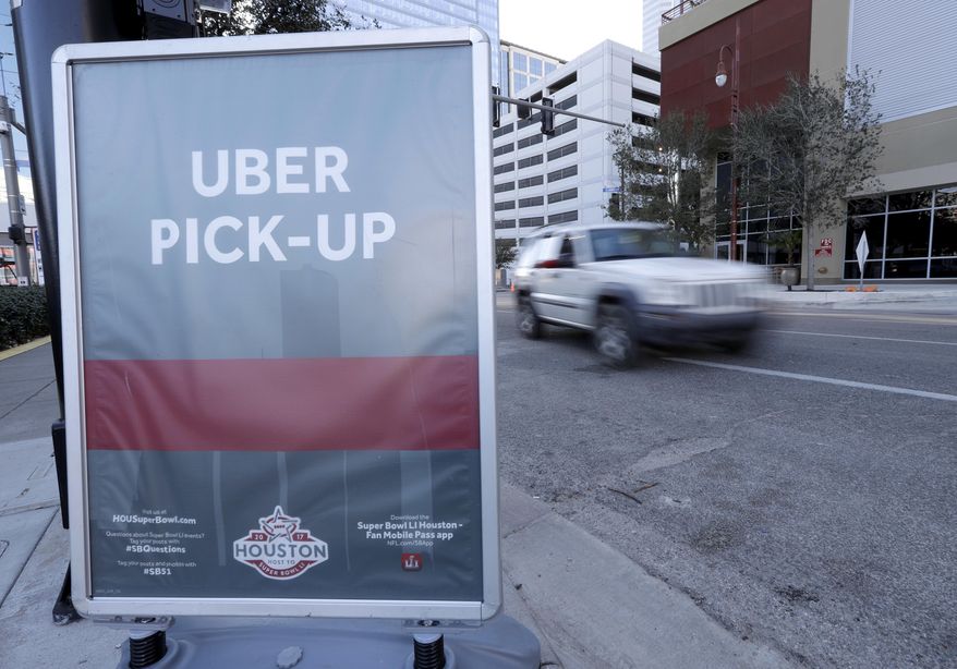 In this Tuesday, Jan. 30, 2017 photo, a sign marks an Uber designated pick-up point near the NFL Experience in downtown Houston. Thanks to the Super Bowl, people taking part in the festivities surrounding the game in Houston will have Uber as one of their transportation choices. The ride sharing service and the city had been at odds over rules regulating how the ride sharing services operates in Houston. (AP Photo/David J. Phillip)