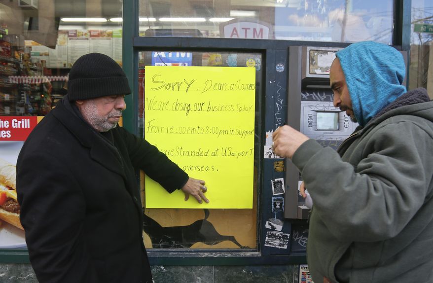 Zamood Zokari, left, and Ali Elazab, right, post a sign on a window of Zokari' family deli in lower Manhattan, alerting customers that the store will close because of a protest against President Donald Trump's travel ban, Thursday, Feb. 2, 2017, in New York. Yemeni business owners who operate corner bodegas and neighborhood delis shut them down on Thursday in protest of the travel ban on people hailing from seven Muslim-majority countries including Yemen. (AP Photo/Bebeto Matthews)