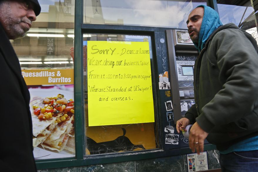 Zamood Zokari, left, and Ali Elazab, right, post a sign on a window of Zokari' family deli in lower Manhattan, alerting customers that the store will close because of a protest against President Donald Trump's travel ban, Thursday, Feb. 2, 2017, in New York. Yemeni business owners who operate corner bodegas and neighborhood delis shut them down on Thursday in protest of the travel ban on people hailing from seven Muslim-majority countries including Yemen. (AP Photo/Bebeto Matthews)