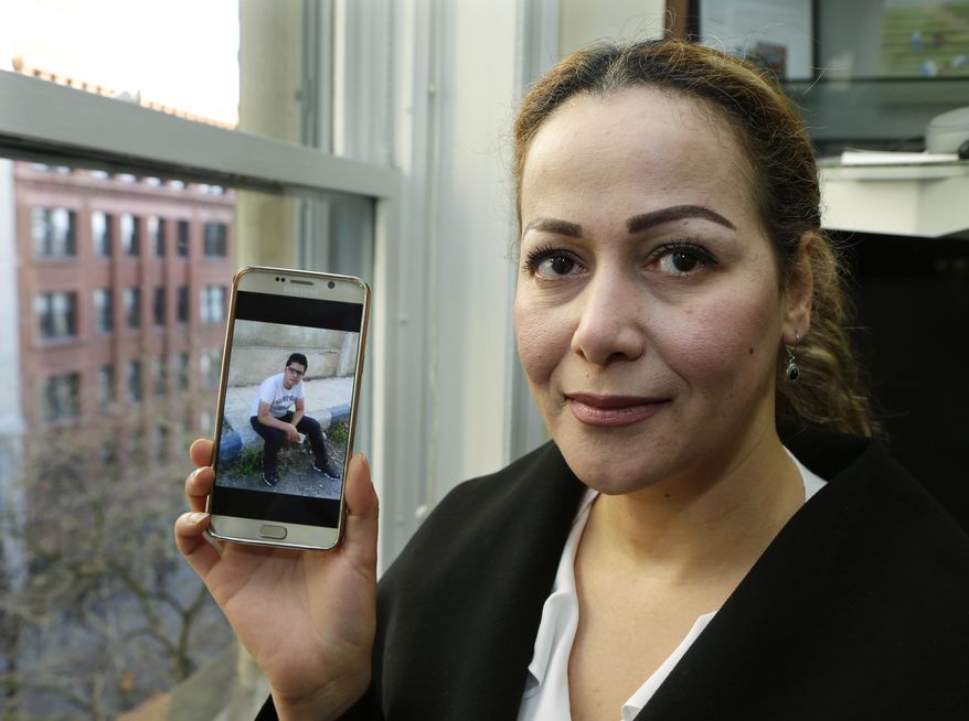 Reema Duhman poses for a photo Wednesday, Feb. 1, 2017, in the offices of the Northwest Immigrant Rights Project in Seattle with a photo of her son displayed on her phone. Duhman, who fled war-torn Syria and now is a lawful permanent U.S. resident who lives in Seattle, had almost completed the complicated process of securing a visa for her 16-year-old son, who is still in Syria, when President Donald Trump issued an executive order prohibiting anyone from Syria and six other countries from traveling to the U.S. Duhman is a plaintiff in a federal class-action lawsuit filed this week by the Northwest Immigrant Rights Project that says Trump's order is unconstitutional and a violation of the Immigration and Nationality Act. (AP Photo/Ted S. Warren)