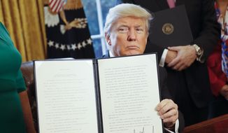 President Donald Trump holds up an executive order after his signing the order in the Oval Office of the White House in Washington on Feb. 3, 2017. The executive order that will direct the Treasury secretary to review the 2010 Dodd-Frank financial oversight law, which reshaped financial regulation after 2008-2009 crisis. (Associated Press) **FILE**