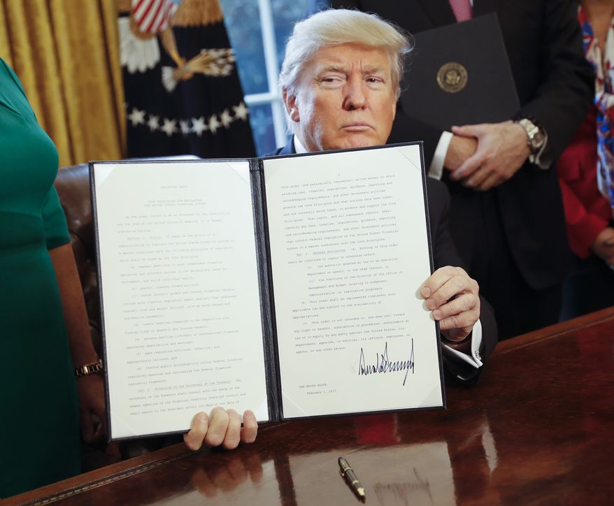 President Donald Trump holds up an executive order after his signing the order in the Oval Office of the White House in Washington on Feb. 3, 2017. The executive order that will direct the Treasury secretary to review the 2010 Dodd-Frank financial oversight law, which reshaped financial regulation after 2008-2009 crisis. (Associated Press) **FILE**