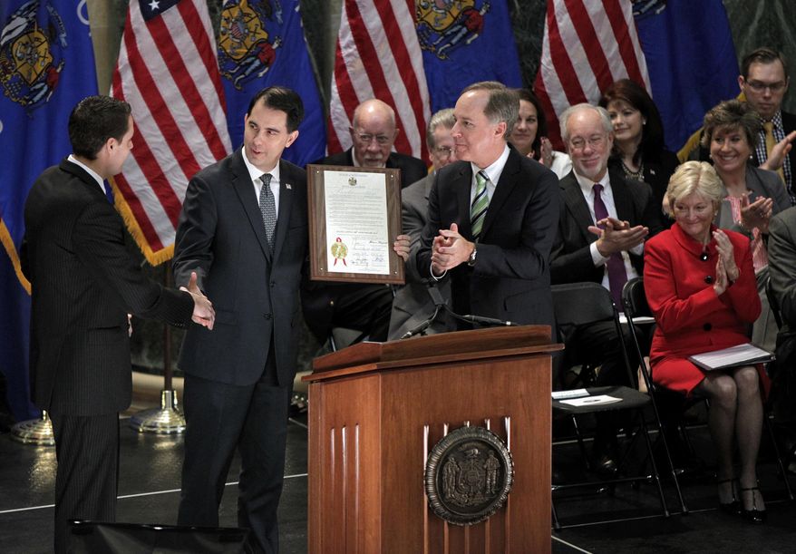 Wisconsin Gov. Scott Walker, center, presents a proclamation to Wisconsin Senate President Roger Roth, R-Appleton, left, and Assembly Speaker Robin Vos, R-Rochester, right, during a 100th anniversary celebration at the State Capitol in Madison, Wis., Tuesday, Jan. 31, 2017. Roth and Vos serve as co-chairs of the Capitol Centennial Commission. (Michael P. King/Wisconsin State Journal via AP)