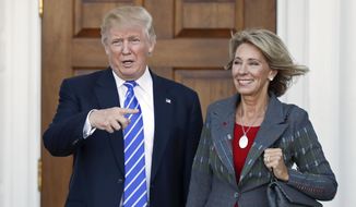 Then-President-elect Donald Trump, left, and Betsy DeVos, right, pose for photographs at Trump National Golf Club Bedminster&#x27;s clubhouse in Bedminster, N.J., in this Nov. 19, 2016, file photo. (AP Photo/Carolyn Kaster, File)