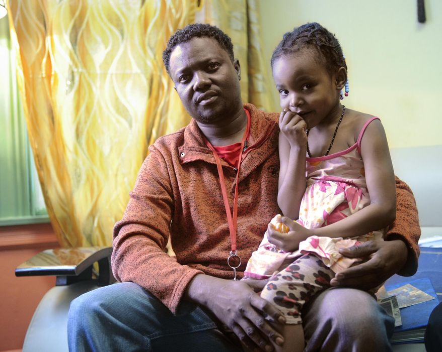 In this Jan. 31, 2017 photo, Mowlid Hussein, a Somali Bantu, poses for a photograph with his daughter Binti Hussein, 4, at their home in Utica, N.Y. Utica has been a refugee "oasis" for decades. Vietnamese, Bosnians, Somalians and Burmese have each found shelter in the city that has benefited from the infusion of house-proud residents who work in hospitals, factories and their own businesses. But now President Donald Trump's executive order crimping the flow of refugees has sent a shudder through the upstate New York city. (AP Photo/Hans Pennink)