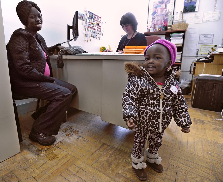 In this Jan. 31, 2017, Arok Deng of Sudan, left, smiles at her American born daughter Leila, as caseworker Azira Tabucic prepares Deng's application for U.S. citizenship at the Mohawk Valley Resource Center for Refugees in Utica, N.Y. Utica has been a refugee "oasis" for decades. Vietnamese, Bosnians, Somalians and Burmese have each found shelter in the city that has benefited from the infusion of house-proud residents who work in hospitals, factories and their own businesses. But now President Donald Trump's executive order crimping the flow of refugees has sent a shudder through the upstate New York city. (AP Photo/Hans Pennink)