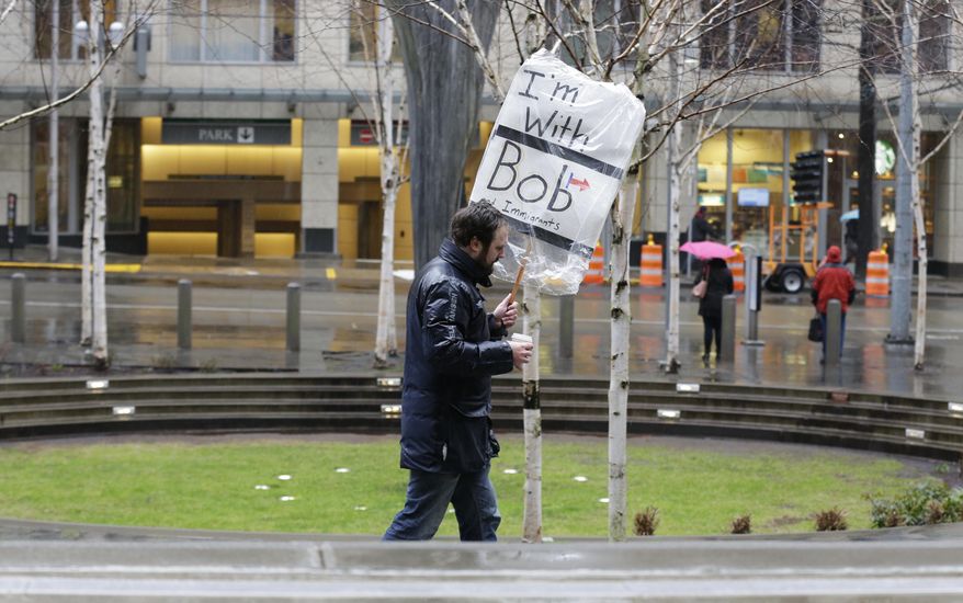 A person walks outside the federal courthouse in Seattle carrying a sign that reads "I'm with Bob and Immigrants," in reference to Washington state Attorney General Bob Ferguson, Friday, Feb. 3, 2017, during a hearing in federal court. A U.S. judge on Friday temporarily blocked President Donald Trump's ban on people from seven predominantly Muslim countries from entering the United States after Washington state and Minnesota urged a nationwide hold on the executive order that has launched legal battles across the country. (AP Photo/Ted S. Warren)