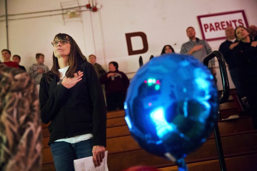 ADVANCE FOR USE TUESDAY, FEB. 7, 2017 AND THEREAFTER-Marlene Kramer stands for the national anthem while watching her stepdaughter cheerlead at a high school wrestling meet in Prairie du Chien, Wis., Thursday, Jan. 19, 2017. Kramer, who voted twice for Obama, used to watch Trump on "Celebrity Apprentice." "I said to myself, ugh, I can't stand him." And when he announced his candidacy, she thought it was a joke. "Then my husband said to me, 'Just think, everything he touches seems to turn to money,'" she said, and she changed her mind. "I'm hoping he'll make this country really rich." (AP Photo/David Goldman)