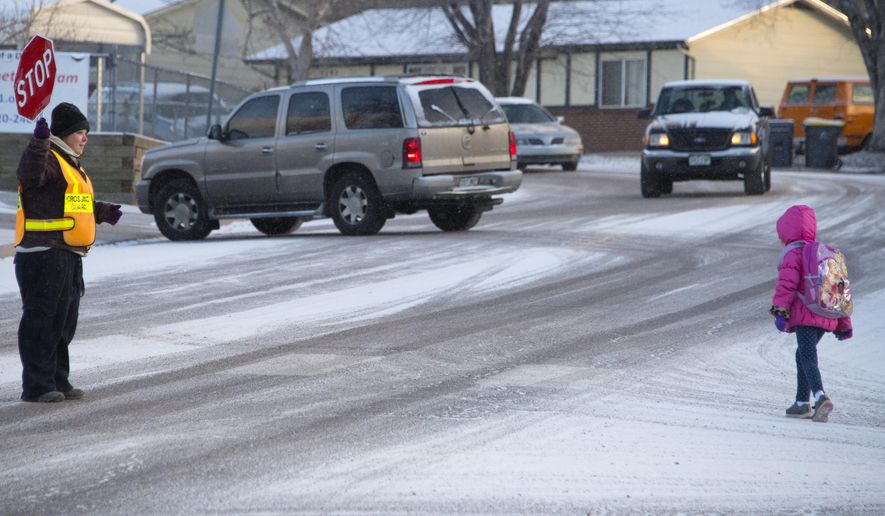 ADVANCE FOR SATURDAY, FEB. 4, 2017 - In this Thursday, Jan. 26, 2017 photo, crossing guard Katrina Deans helps a student cross the road at Fremont Elementary School in Colorado Springs, Colo., School District 11. (Mark Reis /The Gazette via AP)