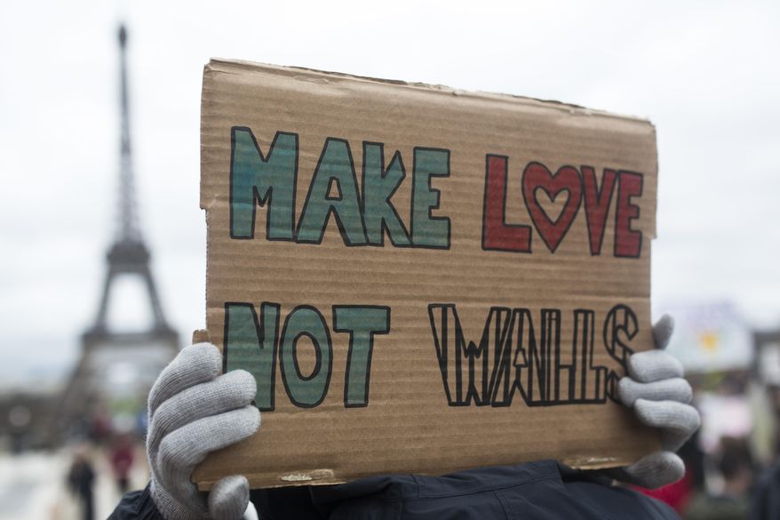 A woman holds a banner reading " Make love not walls" during a gathering to protest U.S. President Donald Trump's recent travel ban to the U.S. at Trocadero Plaza next to the Eiffel Tower in Paris, Saturday, Feb. 4, 2017. People gathered to protest Trump's executive order temporarily banning immigrants from seven Muslim-majority countries from entering the U.S. and suspending the nation's refugee program. (AP Photo/Kamil Zihnioglu)
