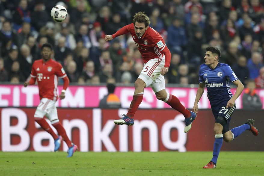 Bayern's Mats Hummels, center, beds the ball besides Schalke's Alessandro Schoepf during the German Bundesliga soccer match between FC Bayern Munich and FC Schalke 04 at the Allianz Arena stadium in Munich, Germany, Saturday, Feb. 4, 2017. (AP Photo/Matthias Schrader)
