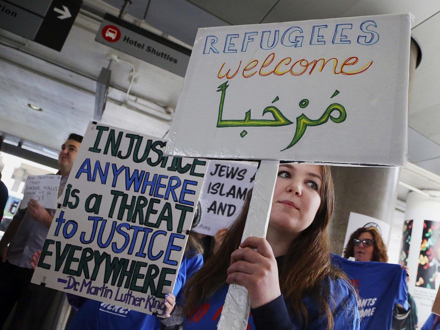 A woman holds a sign saying "welcome" in English and Arabic as demonstrators opposed to President Donald Trump's executive orders barring entry to the U.S. by Muslims from certain countries protest at the Tom Bradley International Terminal at Los Angeles International Airport on Saturday, Feb. 4, 2017. (AP Photo/Reed Saxon)