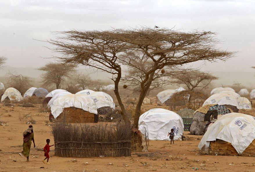 FILE - In this Thursday, Aug. 4, 2011 file photo, refugees walk amongst huts at a refugee camp in Dadaab, Kenya. About 140 Somali refugees whose resettlement in the United States this week was stopped by President Donald Trump's executive order have been sent back to Dadaab refugee camp in northern Kenya, one of the refugees said Saturday, Feb. 4, 2017. (AP Photo/Schalk van Zuydam, File)