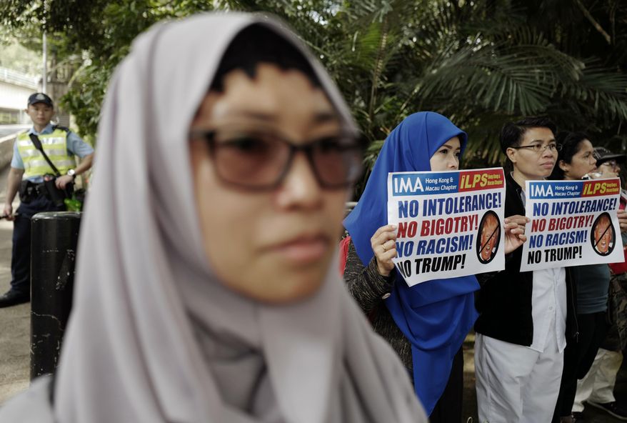 Members of International Migrants Alliance in Hong Kong hold placards during a protest against U.S. President Donald Trump's selective country travel ban outside of the U.S. Consulate in Hong Kong, Sunday, Feb. 5, 2017. (AP Photo/Vincent Yu)