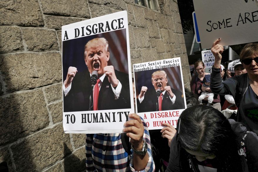 Members of International Migrants Alliance in Hong Kong hold placards during a protest against U.S. President Donald Trump's selective country travel ban outside of the U.S. Consulate in Hong Kong, Sunday, Feb. 5, 2017. (AP Photo/Vincent Yu)