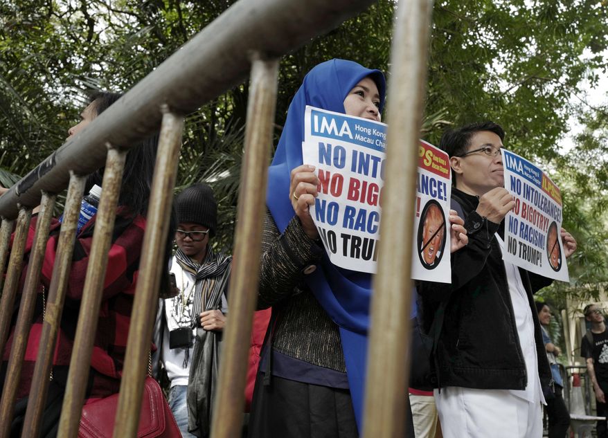 Members of International Migrants Alliance in Hong Kong hold placards during a protest against U.S. President Donald Trump's selective country travel ban outside of the U.S. Consulate in Hong Kong, Sunday, Feb. 5, 2017. (AP Photo/Vincent Yu)