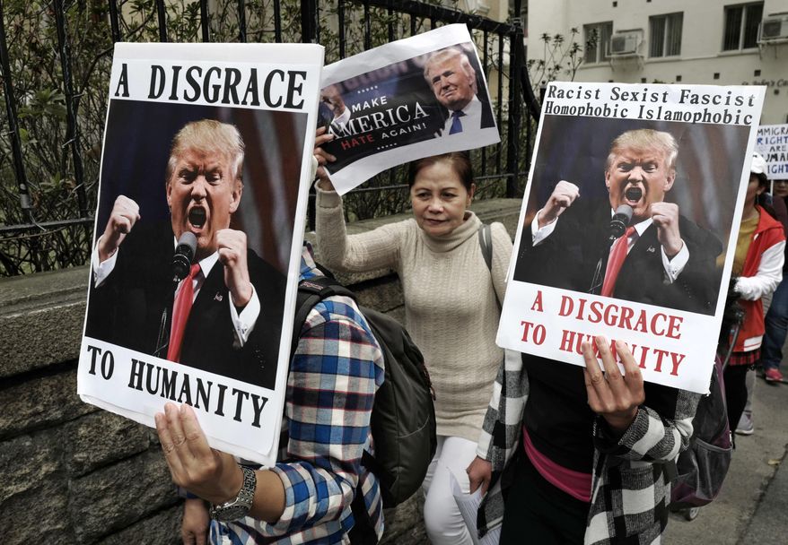 Members of International Migrants Alliance in Hong Kong hold placards during a protest against U.S. President Donald Trump's selective country travel ban outside of the U.S. Consulate in Hong Kong, Sunday, Feb. 5, 2017. (AP Photo/Vincent Yu)