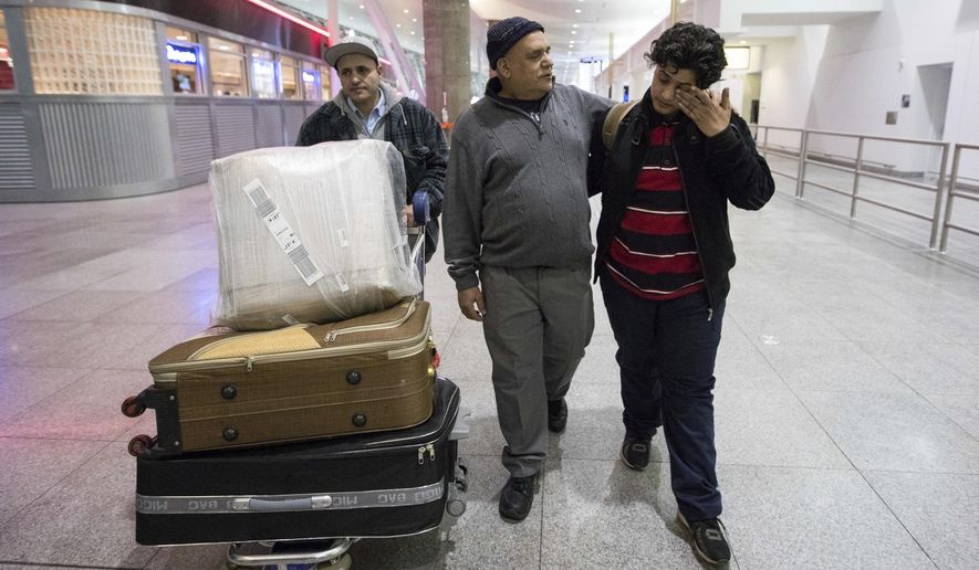 Ali Abdullah Alghazali, 13, right, from Yemen, wipes his eyes as he walks with his father Abdullah Alghazali, left, and his uncle after arrival at John F. Kennedy International Airport in New York, Sunday, Feb. 5, 2017. Travelers from the seven predominantly Muslim countries affected by President Donald Trump's ban enjoyed tearful reunions with family members in the U.S. on Sunday after a federal judge swept the restrictions aside. (AP Photo/Alexander F. Yuan)