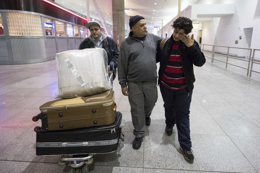 Ali Abdullah Alghazali, 13, right, from Yemen, wipes his eyes as he walks with his father Abdullah Alghazali, left, and his uncle after arrival at John F. Kennedy International Airport in New York, Sunday, Feb. 5, 2017. Travelers from the seven predominantly Muslim countries affected by President Donald Trump's ban enjoyed tearful reunions with family members in the U.S. on Sunday after a federal judge swept the restrictions aside. (AP Photo/Alexander F. Yuan)