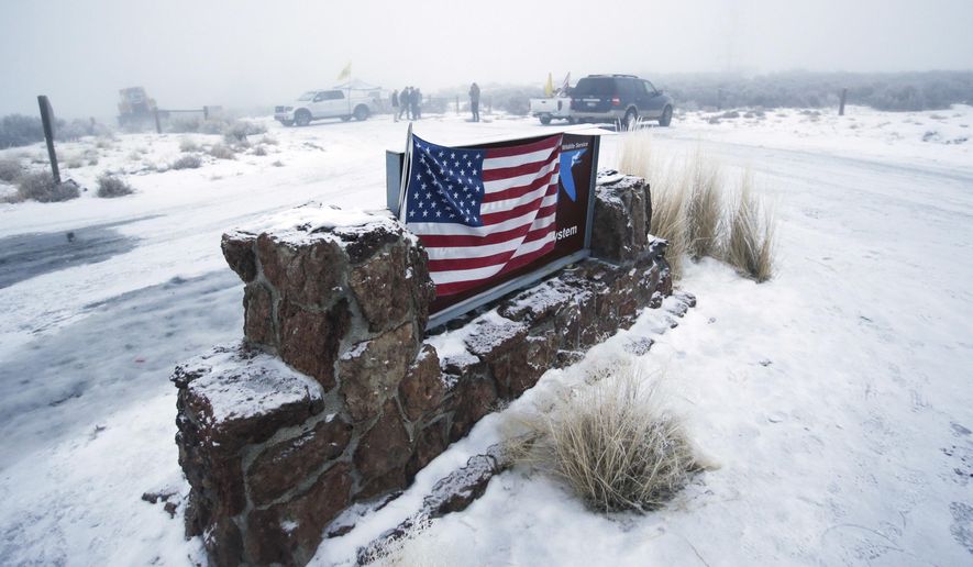 FILE - In this Jan. 7, 2016, file photo, an American flag hangs on the sign at the front entrance of the Malheur National Wildlife Refuge near Burns, Ore. Four of the remaining seven defendants charged in the armed takeover of the refuge are taking plea deals in Portland, Ore., Monday, Jan. 6, 2017, rather than go to trial the following week. (AP Photo/Rick Bowmer, File)