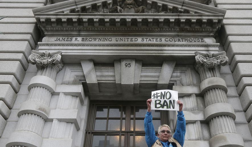 Karen Shore holds up a sign outside of the 9th U.S. Circuit Court of Appeals in San Francisco, Tuesday, Feb. 7, 2017. A panel of appeals court judges reviewing President Donald Trump&#39;s travel ban hammered away Tuesday at the federal government&#39;s arguments that the states cannot challenge the order. (AP Photo/Jeff Chiu)