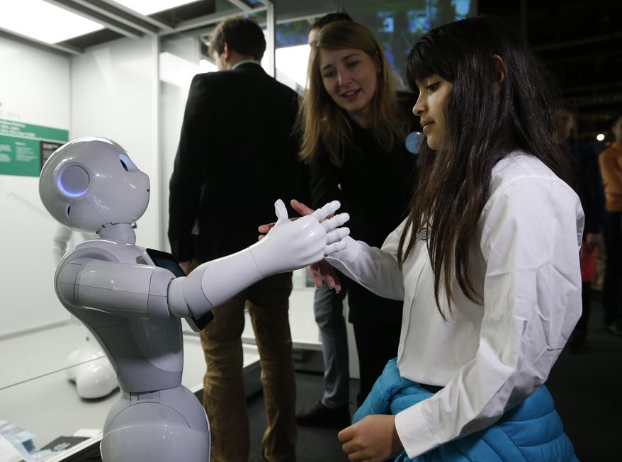 Charllotte Abbot shakes hands with Pepper an interactive French-Japanese robot, during a press preview for the Robots exhibition held at the Science Museum in London, Tuesday, Feb. 7, 2017. The exhibition which shows 500 years of mechanical and robotic advances is open to the public form Feb. 8 through to Sept. 3. (AP Photo/Alastair Grant)