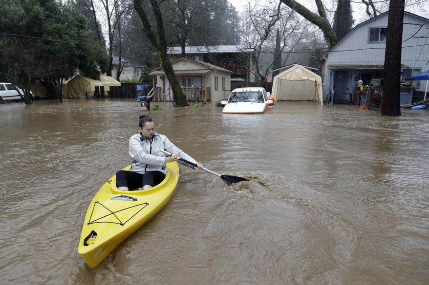 Rachel Turner uses a kayak to access her flooded home Tuesday, Feb. 7, 2017, in Felton, Calif. Flash flood watches are in place for parts of Northern California down through the Central Coast as heavy rains swamp roads and threaten to overtop rivers and creeks. (AP Photo/Marcio Jose Sanchez)