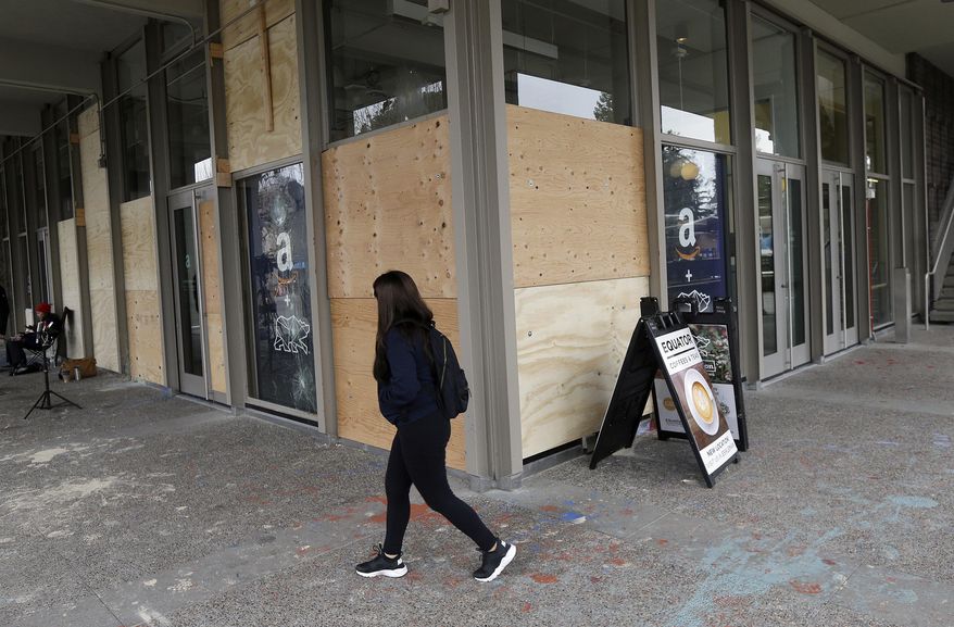 FILE - In this Feb. 2, 2017 file photo, a student walks past boarded-up windows at the Student Union on the University of California, Berkeley campus after demonstrations overnight. UC Berkeley police took a hands-off approach to protesters on the campus last week when violent rioters overtook a largely peaceful protest against a controversial speaker. But that response is being questioned as demonstrators become increasingly hostile and politics are more polarized. (AP Photo/Jeff Chiu, File)