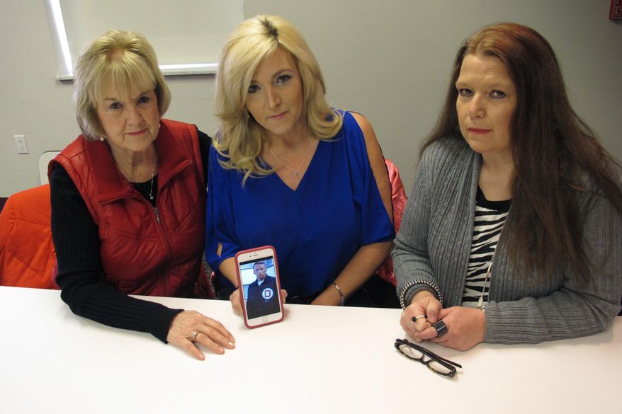 In this Monday, Jan. 30, 2017, photo, Becky Cooper, left, the ex-wife of former Columbus police Officer Niki “Nick” Cooper, and their daughters Amy Cooper, middle, and Lori Cooper display a photo of Niki Cooper from his days on the Columbus, Ohio, police force, in Columbus, Ohio. Niki Cooper was shot in 1972 while interrupting a burglary and never regained full use of his left arm. The family wants the 82-year-old suspect, now living in Dayton, brought to trial. (AP Photo/Andrew Welsh-Huggins)