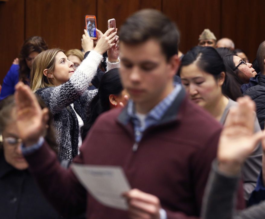 Spectators record their friend or family member out of the 117 immigrants from 37 countries taking the oath of citizenship during a naturalization ceremony Tuesday, Feb. 7, 2017, in Chicago. (AP Photo/Charles Rex Arbogast)