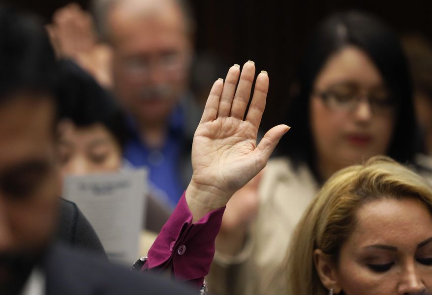 The right hand of Aseel Jan, from Iraq, is raised as she takes the oath of citizenship from U.S. District Judge Sara Ellis, in the Northern District of Illinois, during a naturalization ceremony where 117 immigrants from 37 countries became citizens Tuesday, Feb. 7, 2017, in Chicago. (AP Photo/Charles Rex Arbogast)