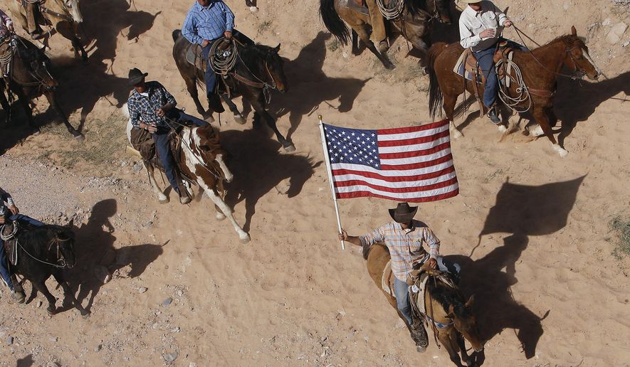 FILE - In this April 12, 2014, file photo, the Bundy family and their supporters fly the American flag as their cattle is released by the Bureau of Land Management back onto public land outside of Bunkerville, Nev. A federal judge in Nevada is considering crucial rulings about what jurors will hear in the trial of six defendants accused of stopping U.S. agents at gunpoint from rounding up cattle near Cliven Bundy's ranch in April 2014. (Jason Bean/Las Vegas Review-Journal, via AP, File)