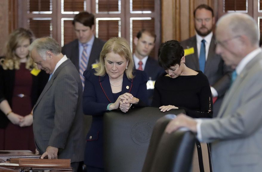 Texas Sen. Sylvia Garcia, D-Houston, and Texas Sen. Donna Campbell, R-New Braunfels, join hands during the opening prayer in the Senate Chamber at the Texas Capitol, Tuesday, Feb. 7, 2017, in Austin, Texas. (AP Photo/Eric Gay)