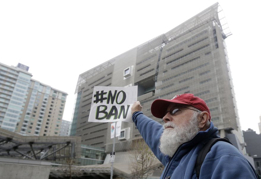David Pearce holds a sign outside of the 9th U.S. Circuit Court of Appeals in San Francisco, Tuesday, Feb. 7, 2017. President Donald Trump's travel ban faced its biggest legal test yet Tuesday as a panel of federal judges prepared to hear arguments from the administration and its opponents about two fundamentally divergent views of the executive branch and the court system. (AP Photo/Jeff Chiu)
