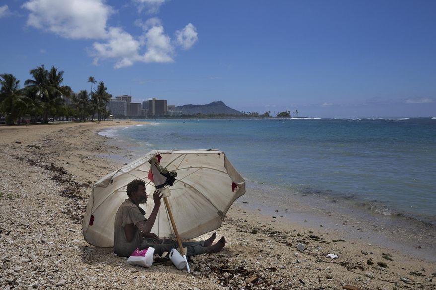 FILE - In this Aug. 27, 2015, file photo, a homeless man drinks water while sitting on the beach at Ala Moana Beach Park located near Waikiki in Honolulu, Hawaii. Hawaii is exploring setting up "safe zones" for homeless people to camp, one of an array of offbeat solutions to its homelessness crisis which ranks worst in the nation. (AP Photo/Jae C. Hong, File)