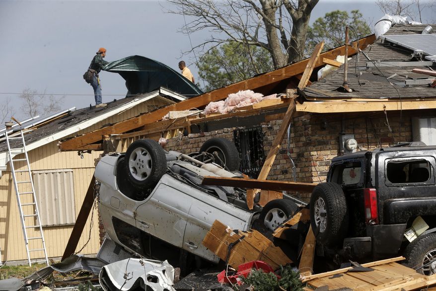 Workers put a tarp on the roof of a damaged home in the aftermath of Tuesday's tornado that tore through the New Orleans East section of New Orleans, Wednesday, Feb. 8, 2017. Officials say tornadoes that struck in southeastern Louisiana destroyed homes and businesses, flipped vehicles and left thousands without power. (AP Photo/Gerald Herbert)
