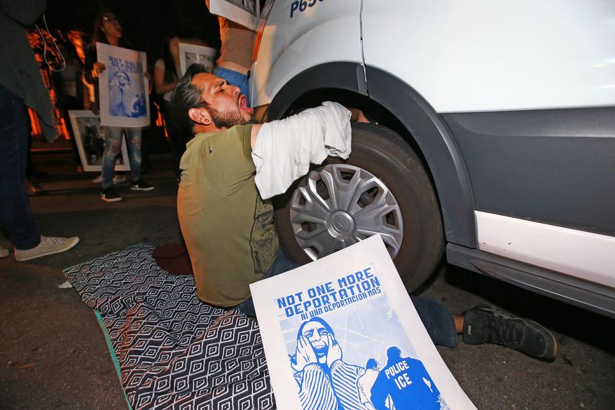 A protester locked himself to the van carrying Guadalupe Garcia de Rayos that is stopped by protesters outside the Immigration and Customs Enforcement facility, Wednesday, Feb. 8, 2017, in Phoenix. Apparently fearing her deportation, activists blocked the gates surrounding the office near central Phoenix in what the Arizona Republic says was an effort to block several vans and a bus inside from leaving. Police arrested several protesters Wednesday night after they blocked enforcement vans. (Rob Schumacher/The Arizona Republic via AP)