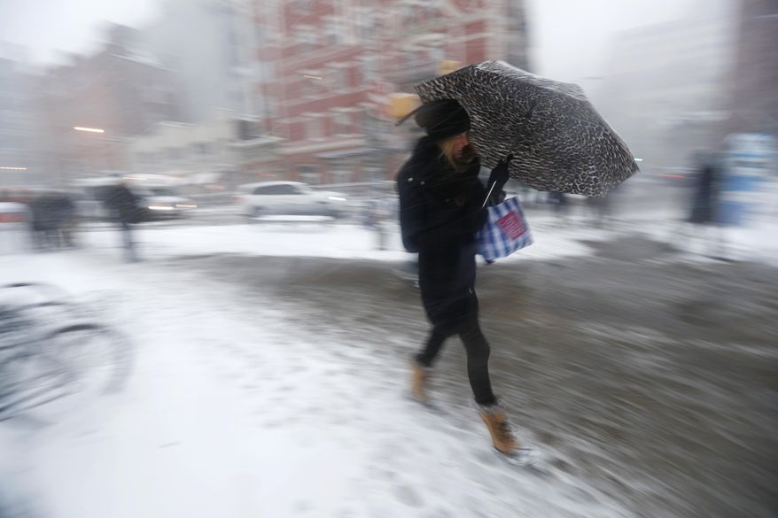 A woman uses an umbrella to shield herself from falling snow while approaching the Hoboken PATH train terminal, Thursday, Feb. 9, 2017, in Hoboken, N.J. A powerful, fast-moving storm swept through the northeastern U.S. Thursday, making for a slippery morning commute and leaving some residents bracing for blizzard conditions. (AP Photo/Julio Cortez)