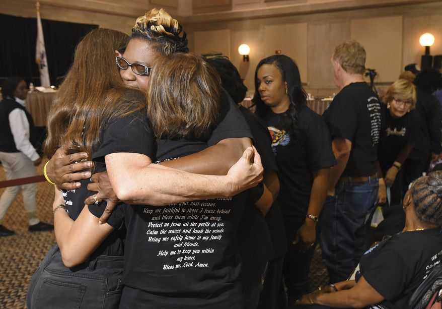 Rochelle Hamm, second from left, the wife of El Faro crew member Frank Hamm, is embraced by the family members of other El Faro crew members after they posed with photographs of their loved ones during a break in a U.S. Coast Guard investigative hearing, Friday, Feb. 10, 2017 in Jacksonville, Fla. The 790-foot freighter heading from Jacksonville, Fla., to San Juan, Puerto Rico sailed into the eye of Hurricane Joaquin near the Bahamas on Oct. 1, 2015 and sank, killing all 33 crew members. (Bob Self/The Florida Times-Union via AP)