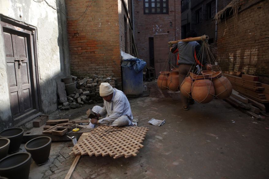 In this Tuesday, Jan. 24, 2017 photo, a Nepalese Prajapati potter carries clay pots for sale in the ancient Nepali town of Thimi. In the past, Prajapati potters would travel across the country to sell their wares. That practice has already died out as more durable material replaced clay pots. Of the nearly 2,000 Prajapati families in town, less than 300 families now depend on clay pottery for a living. (AP Photo/Niranjan Shrestha)