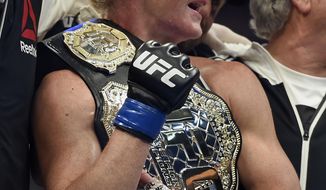FILE - In this Nov. 15, 2015, file photo, Holly Holm holds the champion belt after defeating Ronda Rousey during their UFC 193 bantamweight title fight in Melbourne, Australia. Her leap from obscurity to instant celebrity landed her on daytime talk shows and chatting with late-night hosts and made her _ oh so briefly _ the most talked about fighter in UFC. (AP Photo/Andy Brownbill, File)